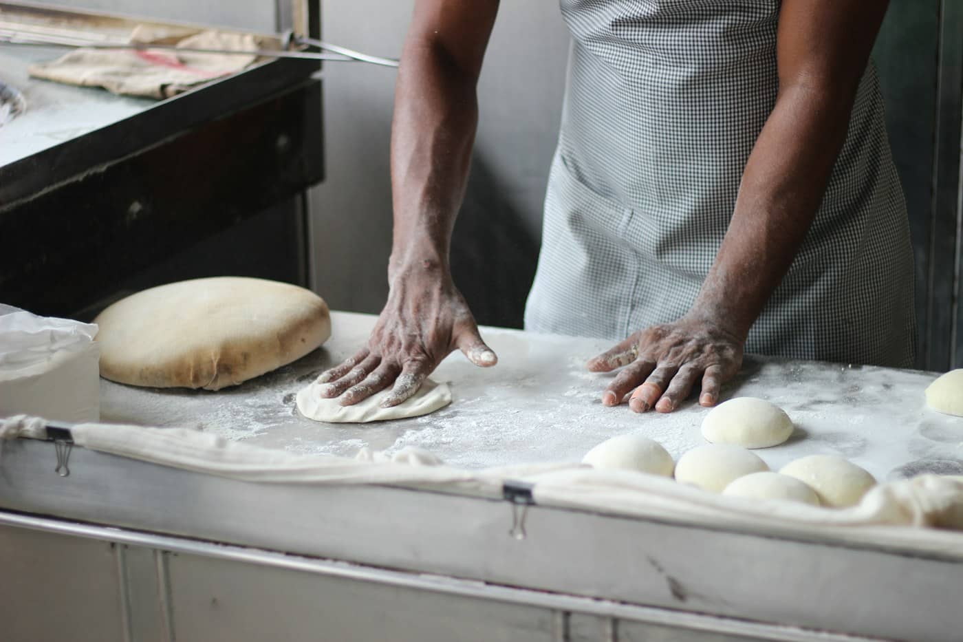 Un boulanger façonne des pâtons sur son plan de travail
