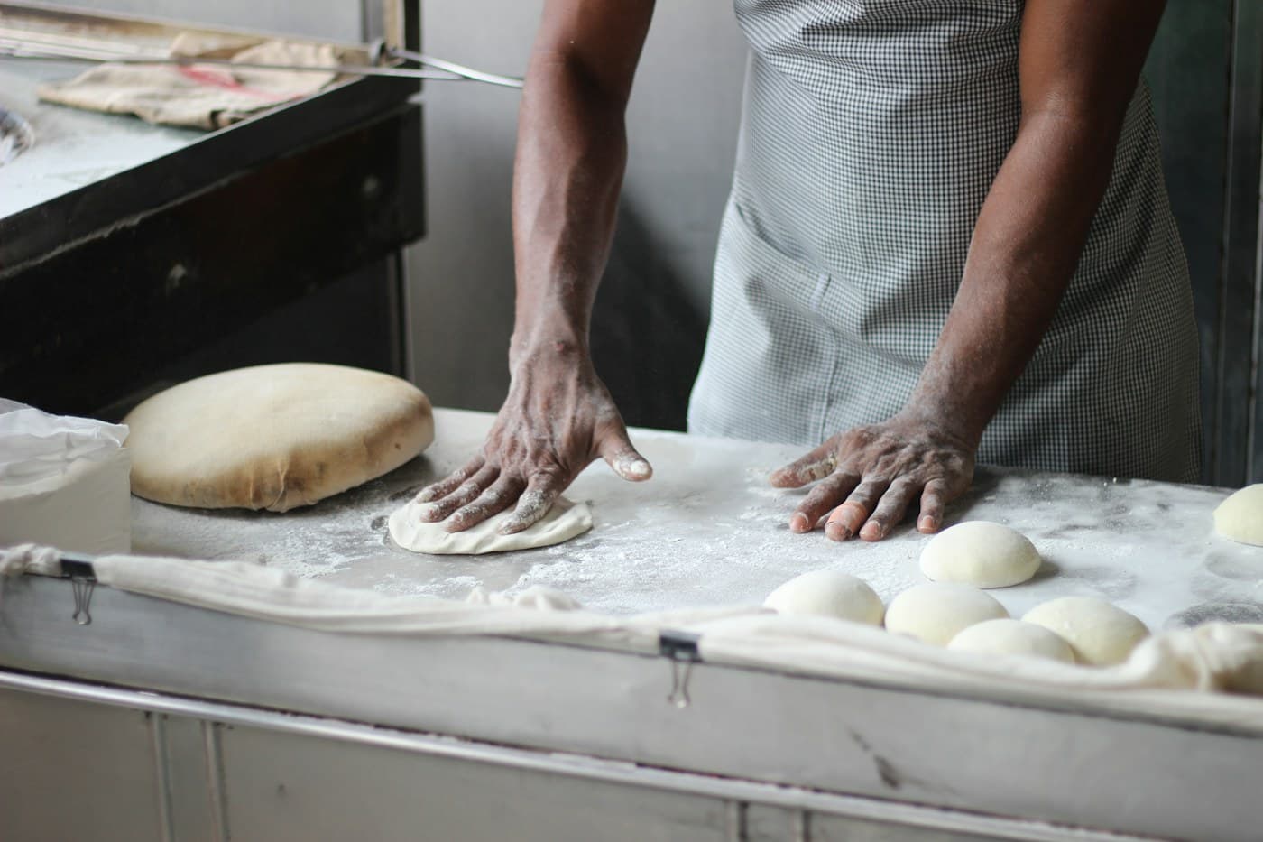 Un boulanger façonne des pâtons sur son plan de travail