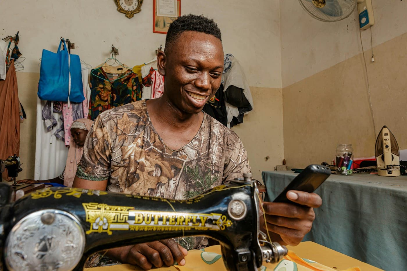 Un jeune tailleur consulte son téléphone à son atelier